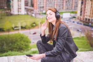 Young handsome eastern brunette girl listening music in a park in the city - technology, freedom, emancipation concept